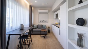 Una cocina moderna con zona de comedor, muebles blancos y un sofá gris.
