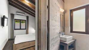 A bedroom with a wooden bed, a window with curtains, and a bedside lamp. - Villa Dali with whirlpool, sauna and 5 bedrooms (Svetvinčenat)