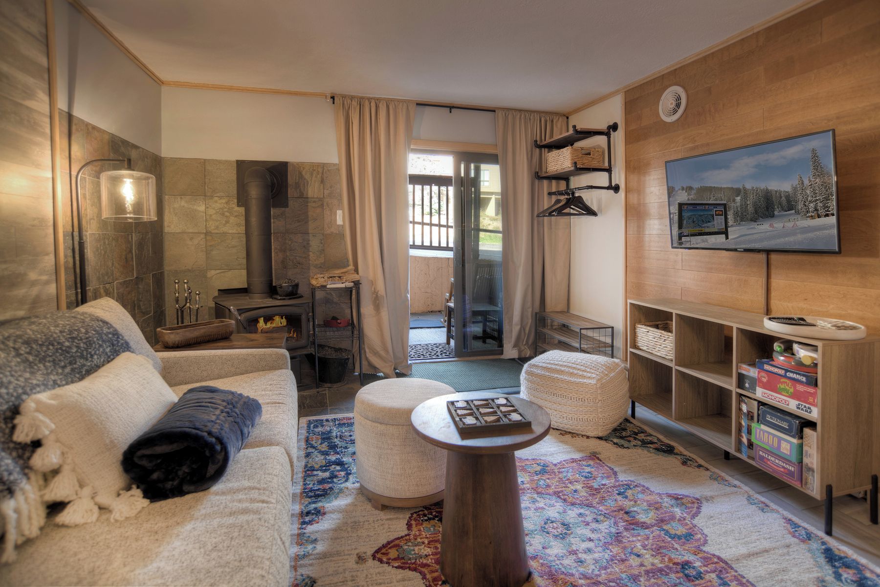 A cozy living room with a fireplace, a sofa, a coffee table, and a TV mounted on the wall.