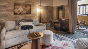 Een gezellige woonkamer met een open haard, een bank, een salontafel en een vloerkleed.