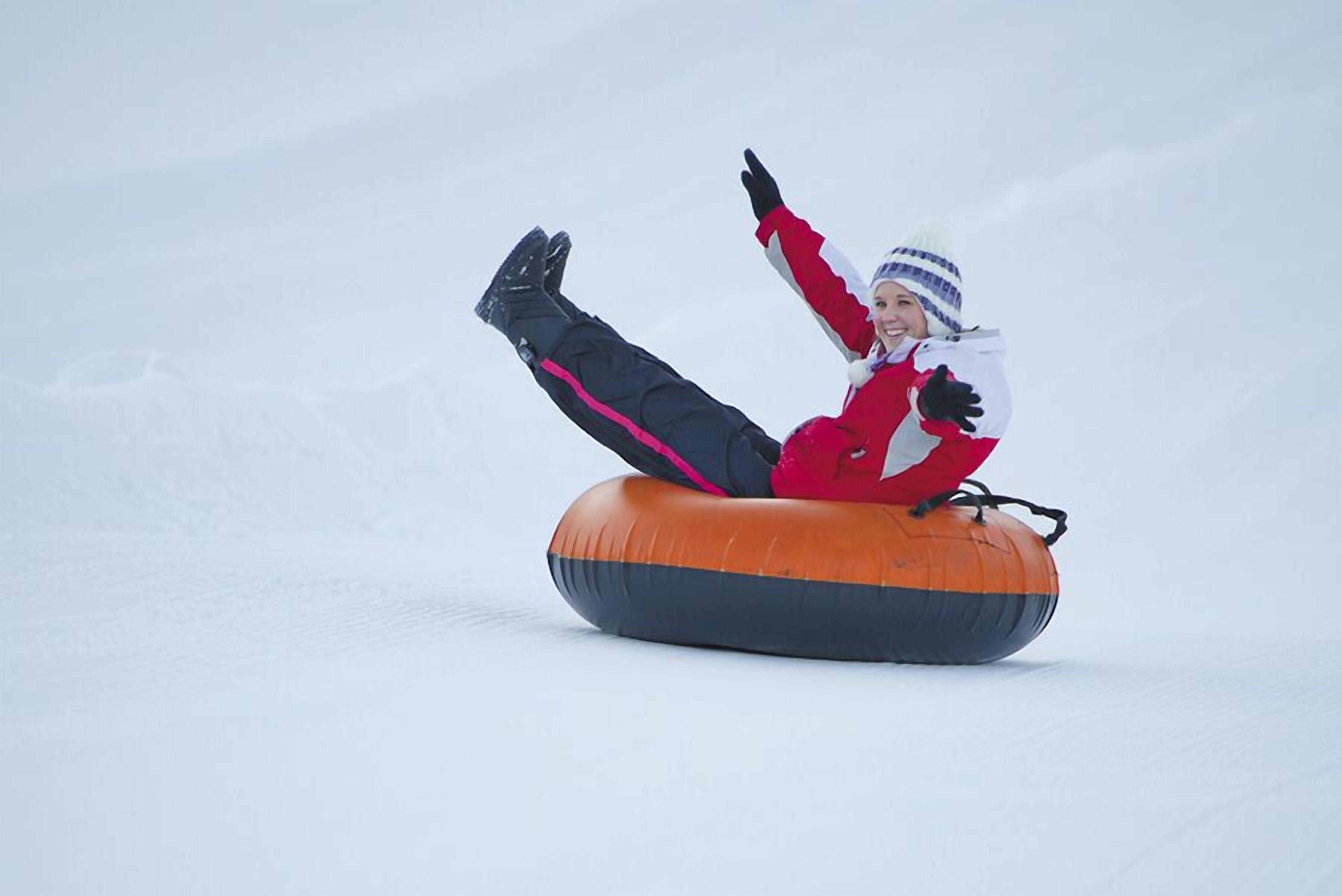 A person on a snow tube in a snowy environment.