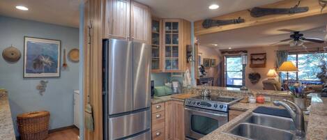 A kitchen with wooden cabinets, stainless steel appliances, granite countertops, and a view of the outdoors.