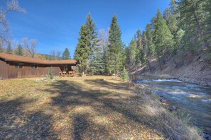 A cabin with a deck and a river in the background.