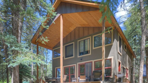 A two-story cabin with a wooden deck, large windows, and a stone foundation. - Creekside Retreat - Waterfront Home 20 Minutes from Downtown Durango (Durango)