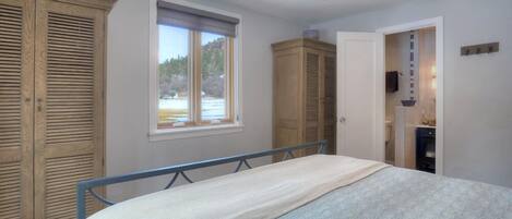 Ein Schlafzimmer mit Bett, Deckenventilator, Fenster und Holzschränken.