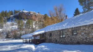 Ein Steinhaus mit verschneitem Dach und einer Holzveranda.