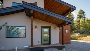 A modern two-story house with a green door, a large window, and a wooden deck. - Mountain Home w/Amazing Views - 12 Min. to Durango - Central AC - EV Charger (Durango)
