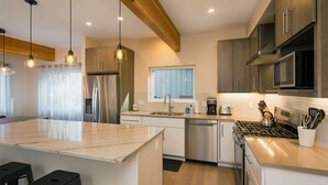 A modern kitchen with a central island, stainless steel appliances, and pendant lighting. - Mountain Home w/Amazing Views - 12 Min. to Durango - Central AC - EV Charger (Durango)