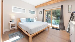 A bedroom with a large bed, wooden beams, a sliding glass door to a garden, a small desk, and a dresser. - Mountain Home w/Amazing Views - 12 Min. to Durango - Central AC - EV Charger (Durango)