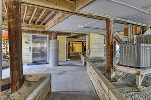 An interior with exposed wooden beams, a concrete pillar, and a large air conditioning unit.