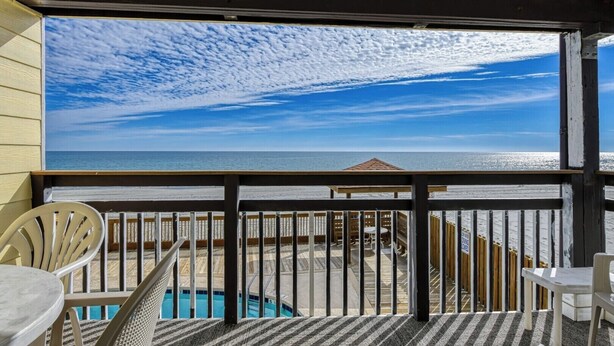 A balcony with a view of the beach and ocean, featuring a pool and outdoor seating. - Afterdeck 104 - Two Bedroom, Two Bath Oceanfront Condo (Garden City Beach)