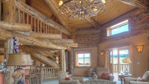 Un intérieur rustique avec un plafond en bois, un lustre et un coin salon agrémenté de canapés à motifs.