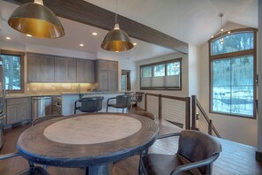 A modern kitchen with a central island, pendant lighting, and large windows offering a view of the outdoors.