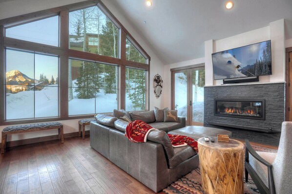 A modern living room with a large window, a fireplace, and a television.