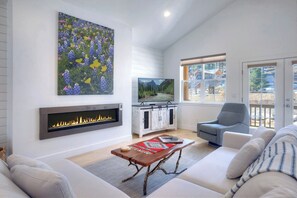A modern living room with a fireplace, a television, a sofa, and a large window.