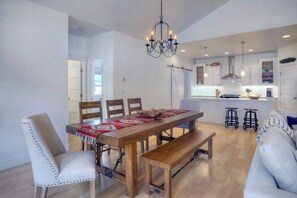 A spacious kitchen with a wooden table, bar stools, and a chandelier. - New Contemporary Mountain Home - 12 Min. to Durango - Central AC - Views (Durango)