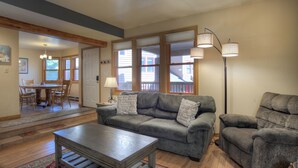 A living room with a gray sofa, two armchairs, a wooden coffee table, and a floor lamp. There is a dining area with a table and chairs visible through an open door. - Mesa Haven | Downtown Durango Access, Pool/Hot Tub, Near FLC and Golf (Durango)