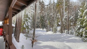 A wooden cabin with a snow-covered landscape and trees in the background.