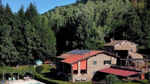 Une maison en pierre avec un toit rouge, une piscine et un jardin.