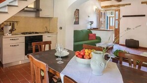 Une cuisine compacte avec un coin repas, un canapé vert et un escalier.