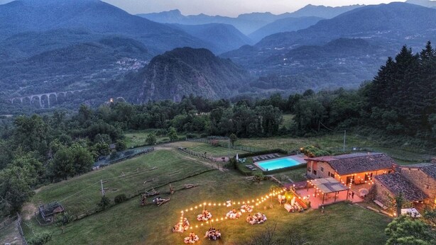 Un cadre rural avec une piscine, un espace clos aménagé avec des sièges et un bâtiment éclairé.