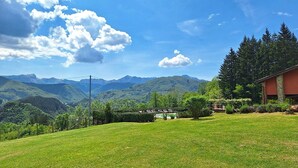Un champ herbeux avec un bâtiment et des montagnes en arrière-plan.