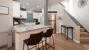 A modern kitchen with a marble countertop, stainless steel appliances, and a central island with bar stools.