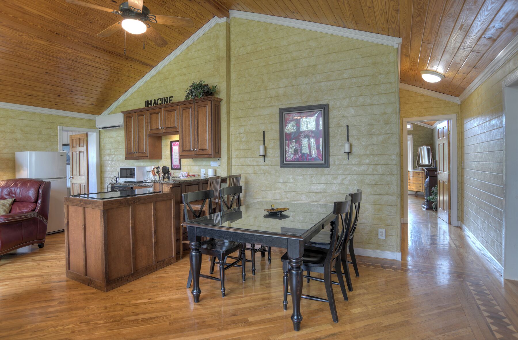 A spacious kitchen with wooden cabinets, a dining table with chairs, and a high ceiling with exposed beams.