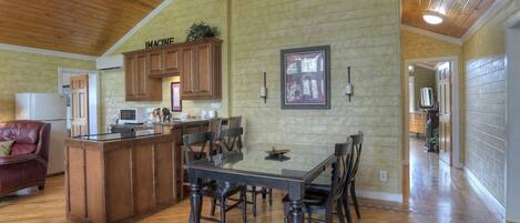 A spacious kitchen with wooden cabinets, a dining table with chairs, and a high ceiling with exposed beams.