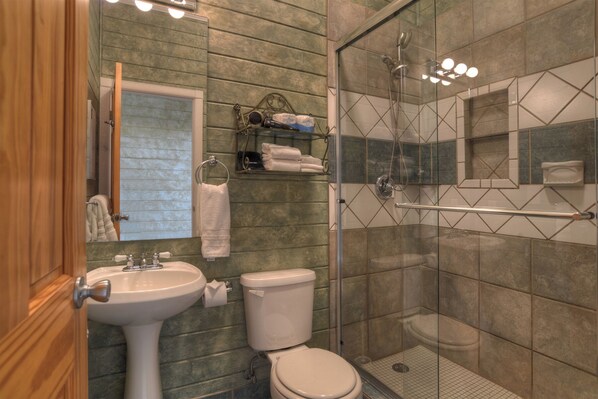 A bathroom with a glass-enclosed shower, a sink, and a toilet.