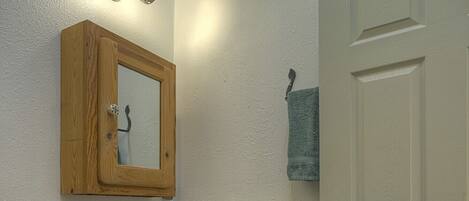 A bathroom with a wooden vanity, a sink, a mirror, and a door.
