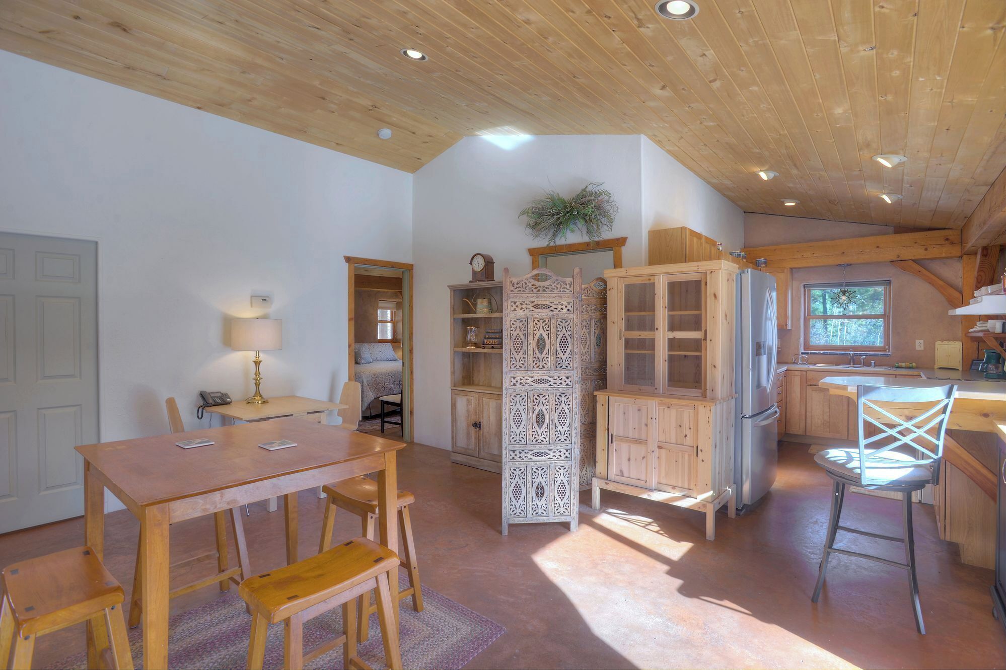Een landelijke keuken met houten kasten, een koelkast en een eethoek met een tafel en stoelen.