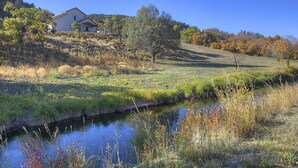 Une maison située sur une colline, avec un petit ruisseau au premier plan.