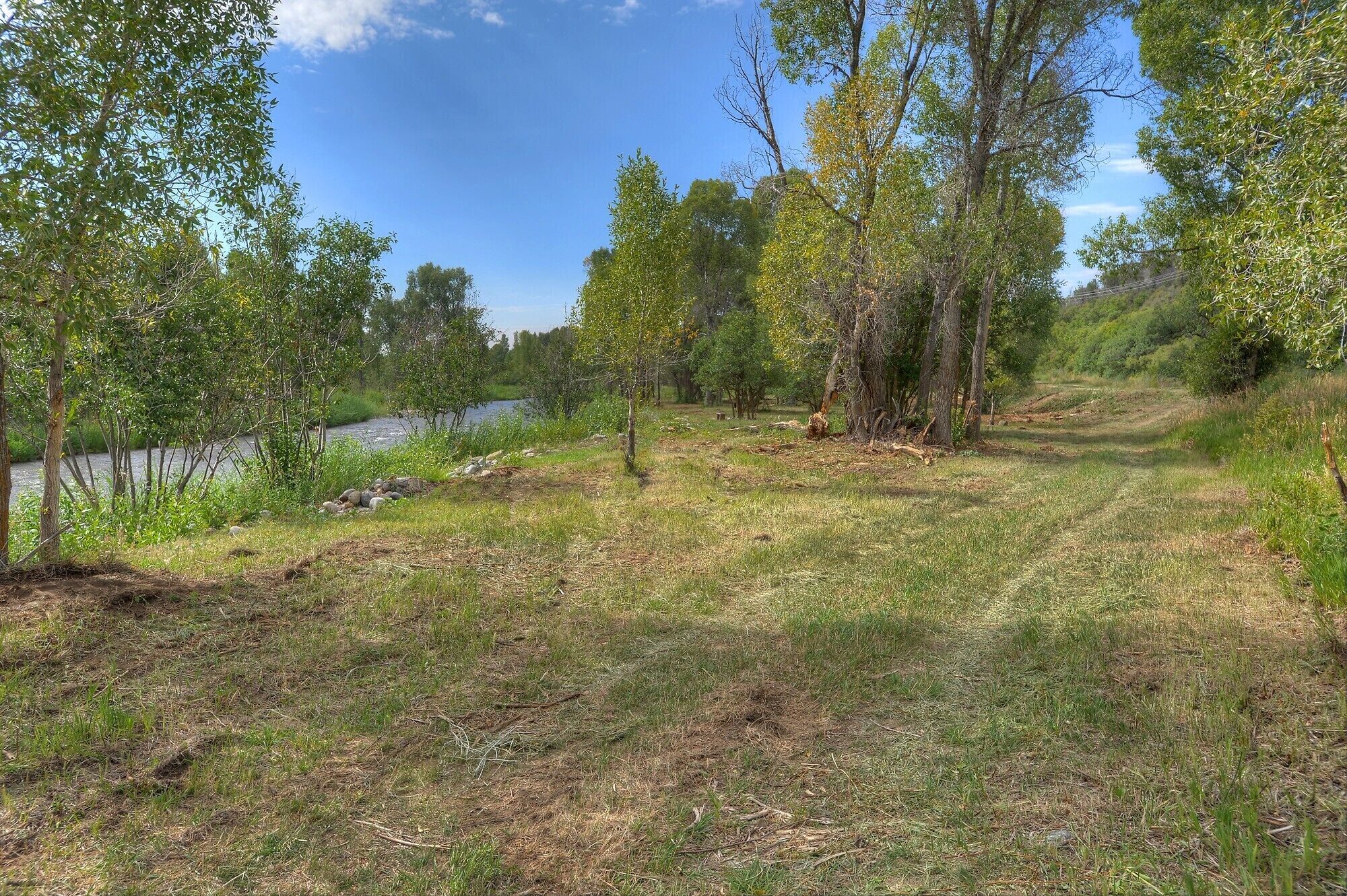 A natural landscape with a river, trees, and grassy terrain.