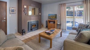 Een woonkamer met een open haard, een bank, een salontafel en een televisie.