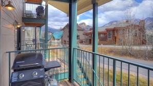 Un espace extérieur abrité avec un barbecue, un balcon offrant une vue sur les montagnes et une rambarde.