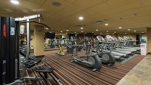Une salle de sport équipée de tapis de course, de vélos elliptiques et d'appareils de musculation.