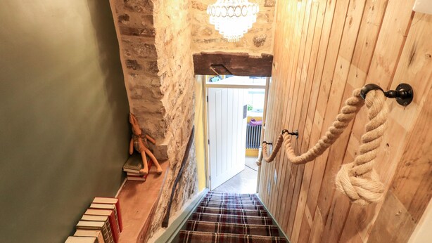 A staircase with a wooden handrail and a chandelier.