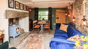 A cozy living room with a stone fireplace, a blue sofa, and a dining area with wooden furniture.