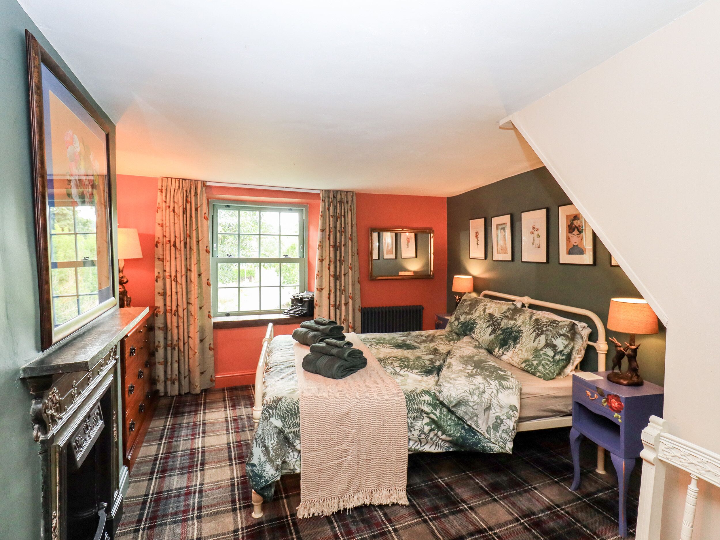 A bedroom with a bed, a dresser, a window, and a radiator.