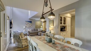 Una sala moderna con comedor, un conjunto de sofás y una cocina visible a través de una puerta abierta.