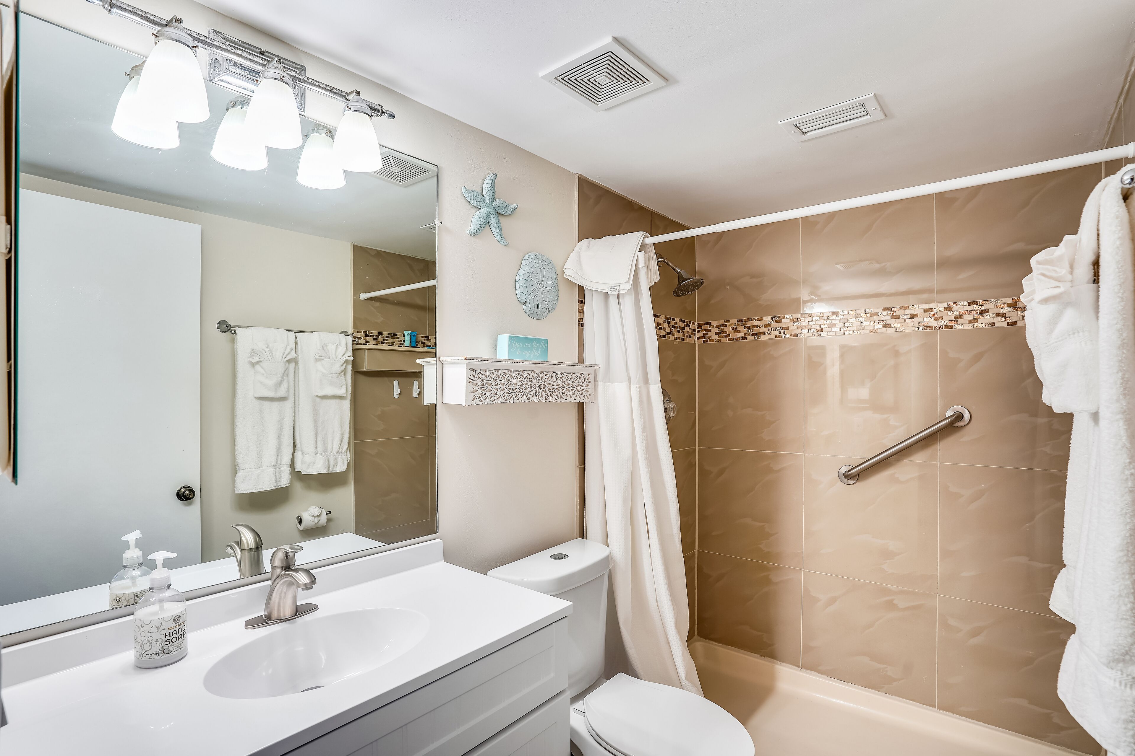 A bathroom with a white sink, a mirror, a shower with a glass door, and a towel rack.