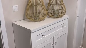 A white cabinet with two wicker lamps on top and a light switch on the wall.
