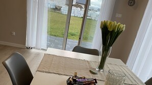A dining area with a table set for two, a vase with flowers, and a plate of chocolates.