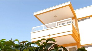 Un edificio moderno con tetto piatto e un balcone.