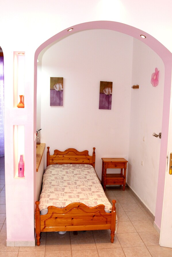Un dormitorio con una cama de madera, una mesita de noche pequeña y dos cuadros colgados en la pared.