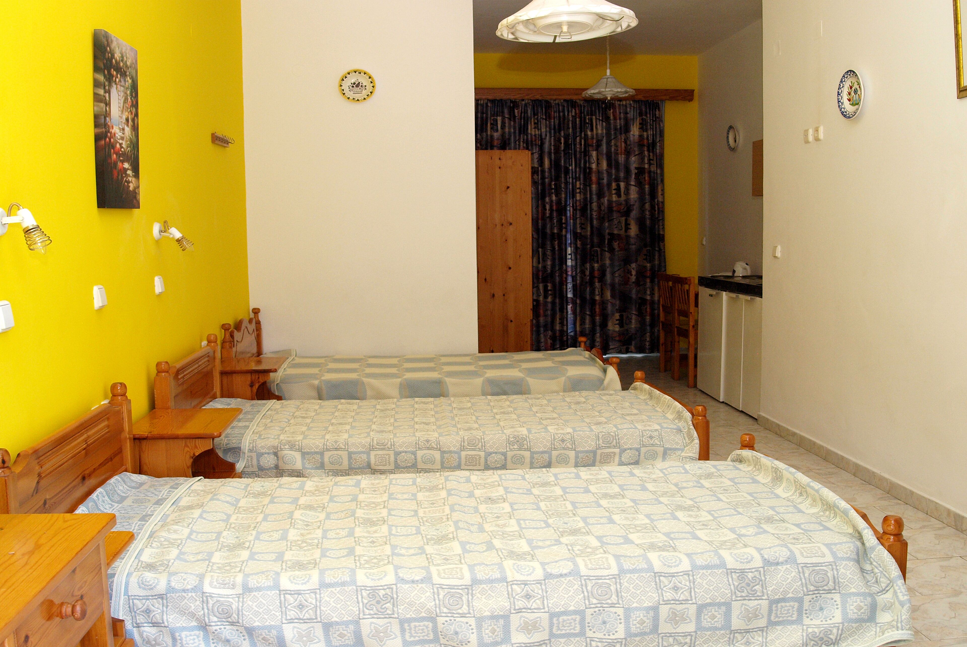 Una habitación con dos camas, muebles de madera, zona de comedor y cocina.