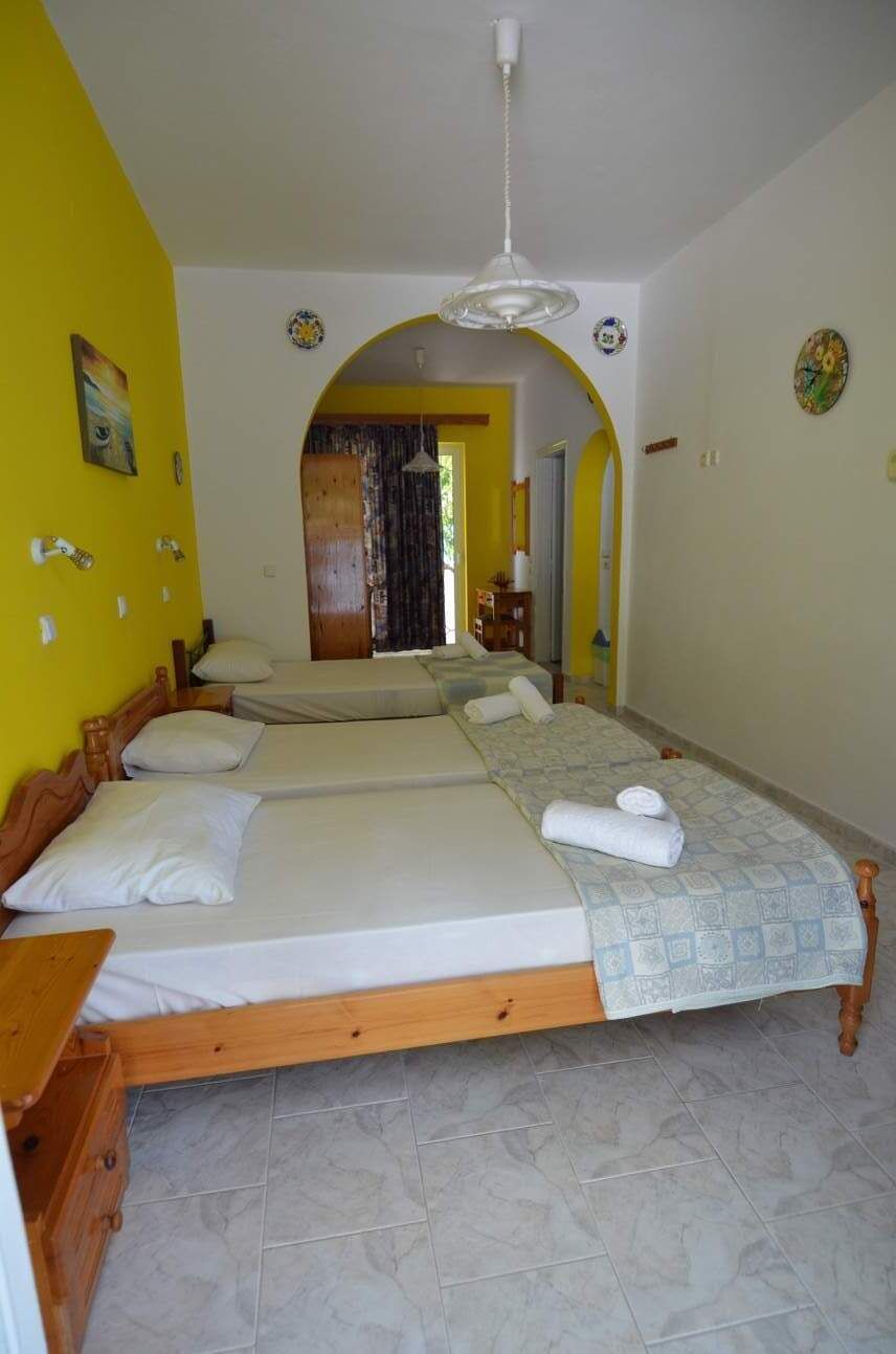 A room with three beds, wooden headboards, and a tiled floor.
