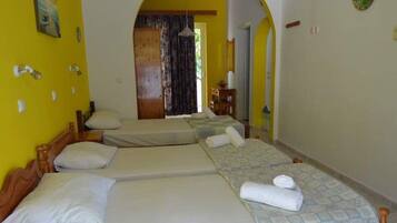 A room with three beds, wooden headboards, and a tiled floor.