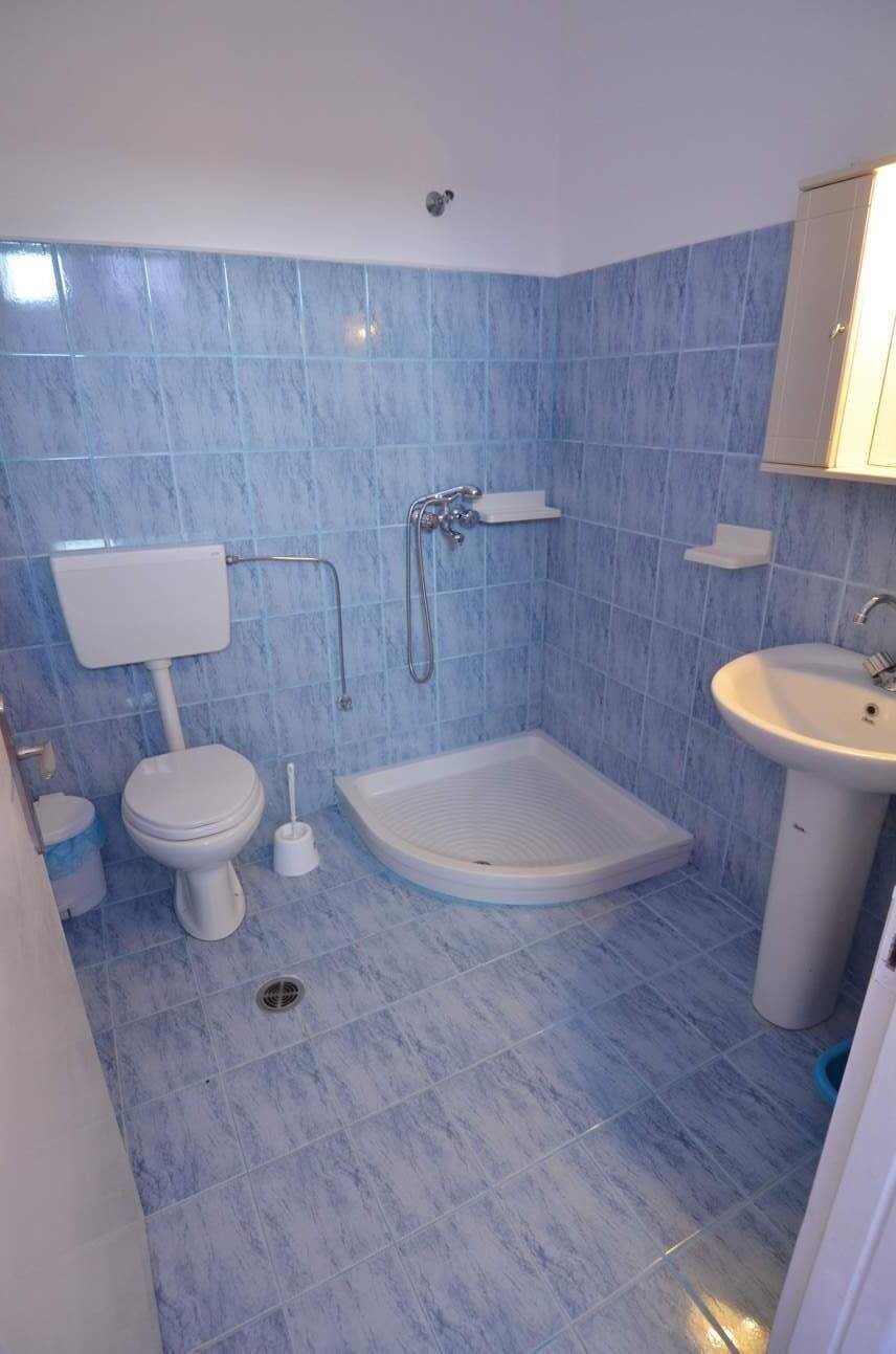 A bathroom with a toilet, shower, and sink.